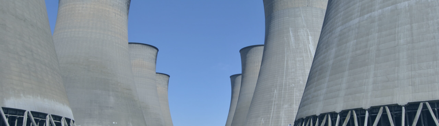 Row of natural-draft hyperbolic cooling towers photographed from below against a clear blue sky