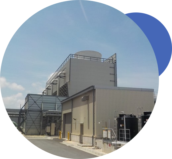 Circular-masked photograph of an industrial cooling installation beside a plant building